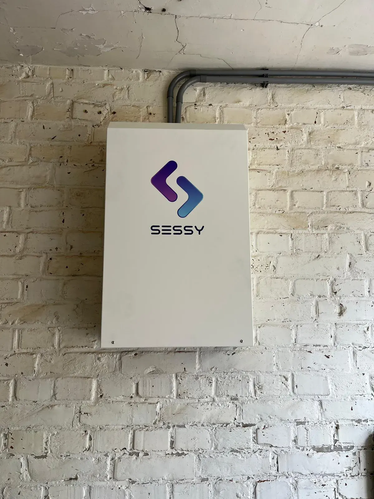 Sessy thuisbatterij op witte bakstenen muur